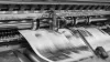 A printing press printing newspapers at speed, the newspaper is blurred.